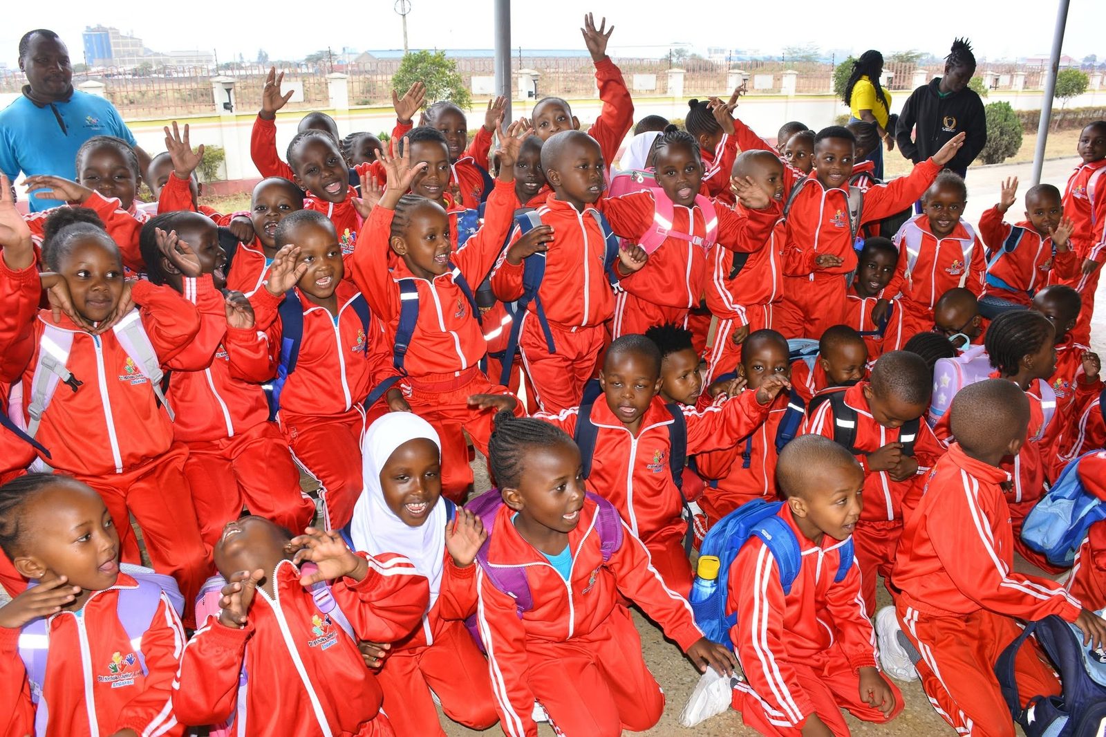St. Nicholas learners waving and smiling in red uniform